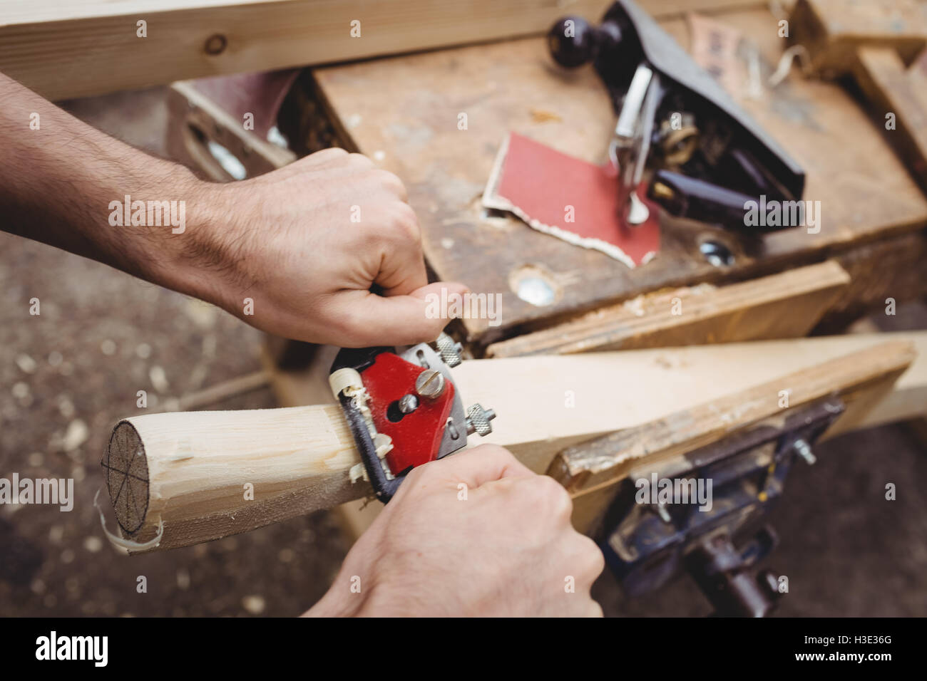 Uomo che utilizza un attrezzo portatile per rendere liscia e il livello della superficie di una tavola Foto Stock