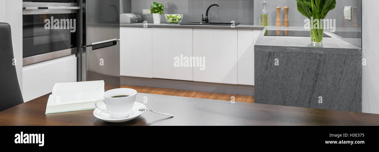 Panorama della tazza di caffè sul tavolo da pranzo in legno in piedi in bianco, cucina moderna Foto Stock