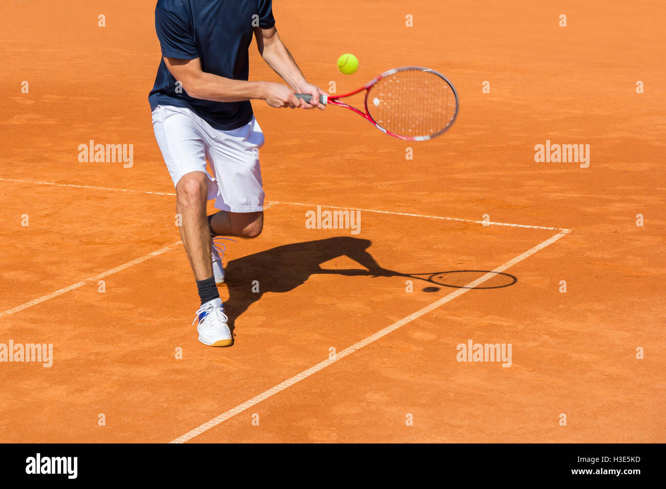 Tennista in azione sulla corte di argilla in una giornata di sole Foto Stock