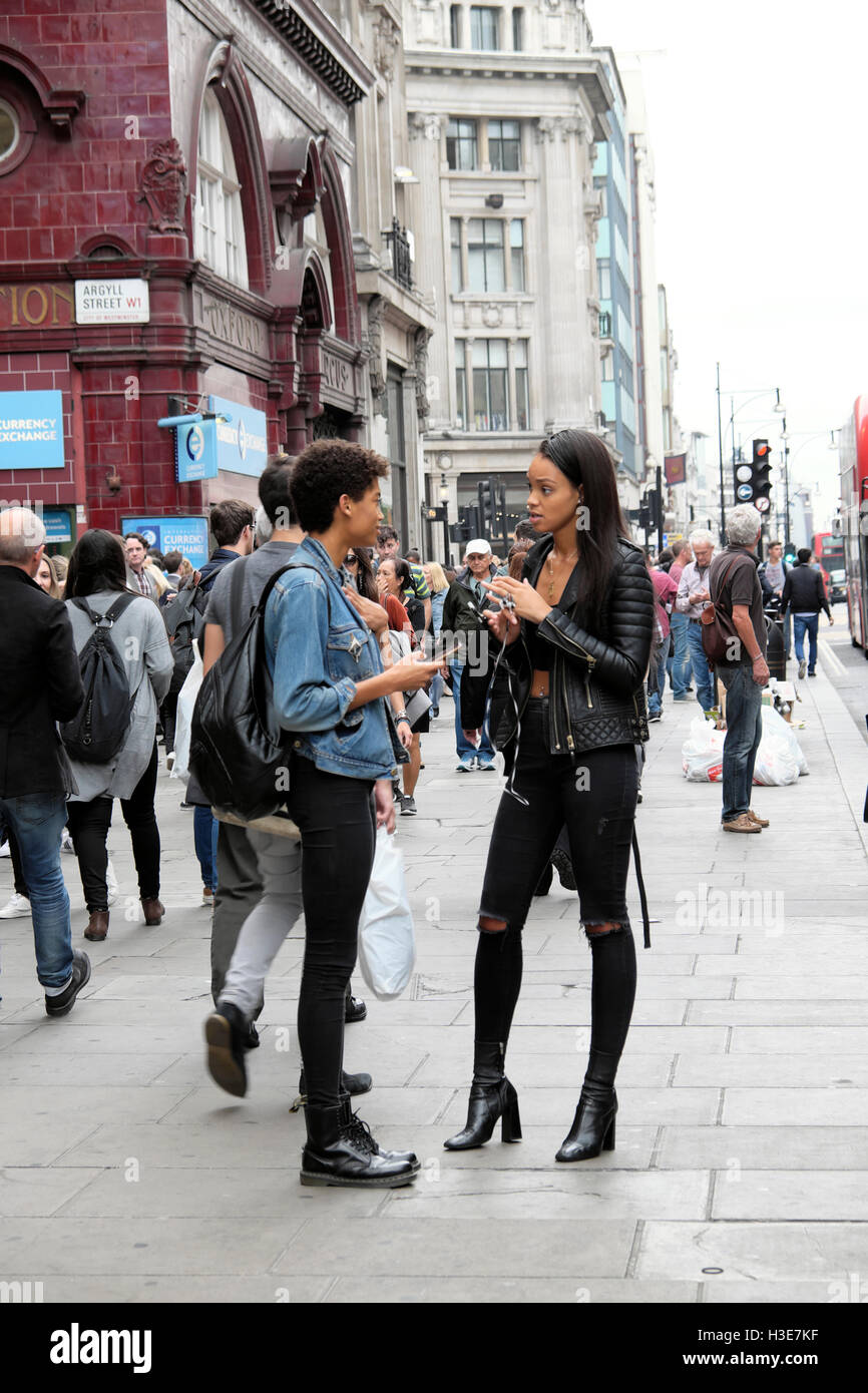 Alla moda di giovani donne inglesi in una conversazione mentre la gente a piedi da Oxford Street vicino a Oxford Circus in London W1 Inghilterra UK KATHY DEWITT Foto Stock