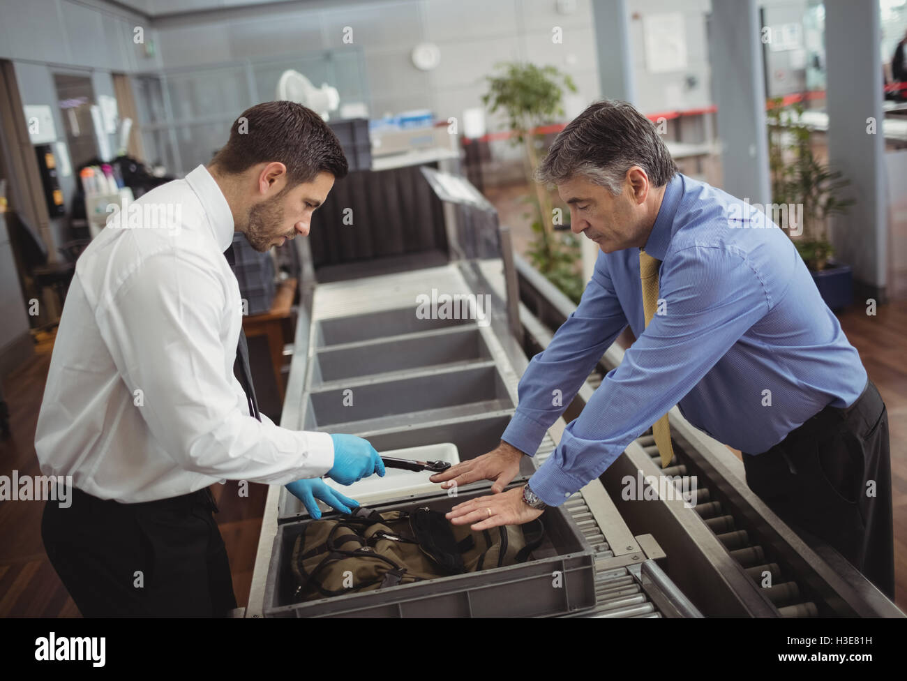Aeroporto ufficiale di sicurezza utilizzando un rilevatore di metalli per verificare la presenza di un sacchetto Foto Stock