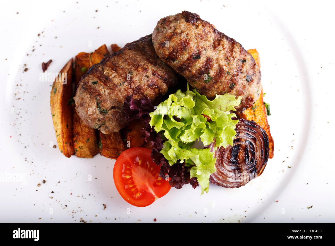 Un piatto a base di carne e patate e erbe su una piastra bianca Foto Stock