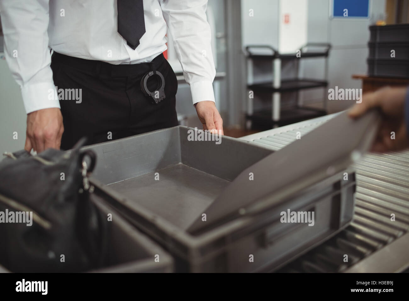 L'uomo mettendo laptop nel vassoio per il controllo di sicurezza Foto Stock
