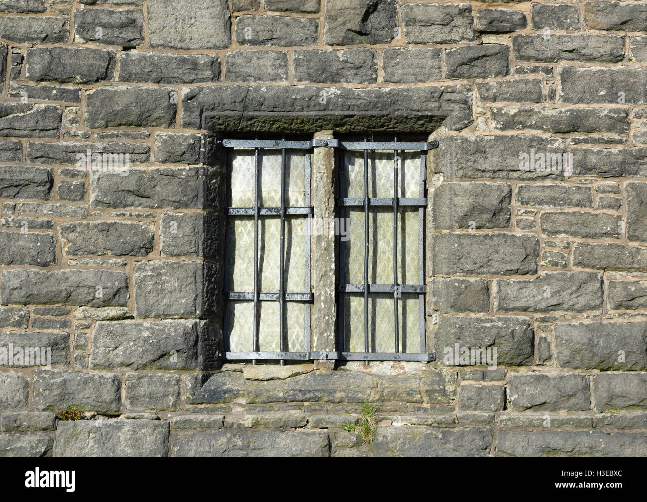 Finestre a mullioned in pietra con griglia in ferro su muro in pietra, Peel Memorial torre in Bury lancashire uk Foto Stock