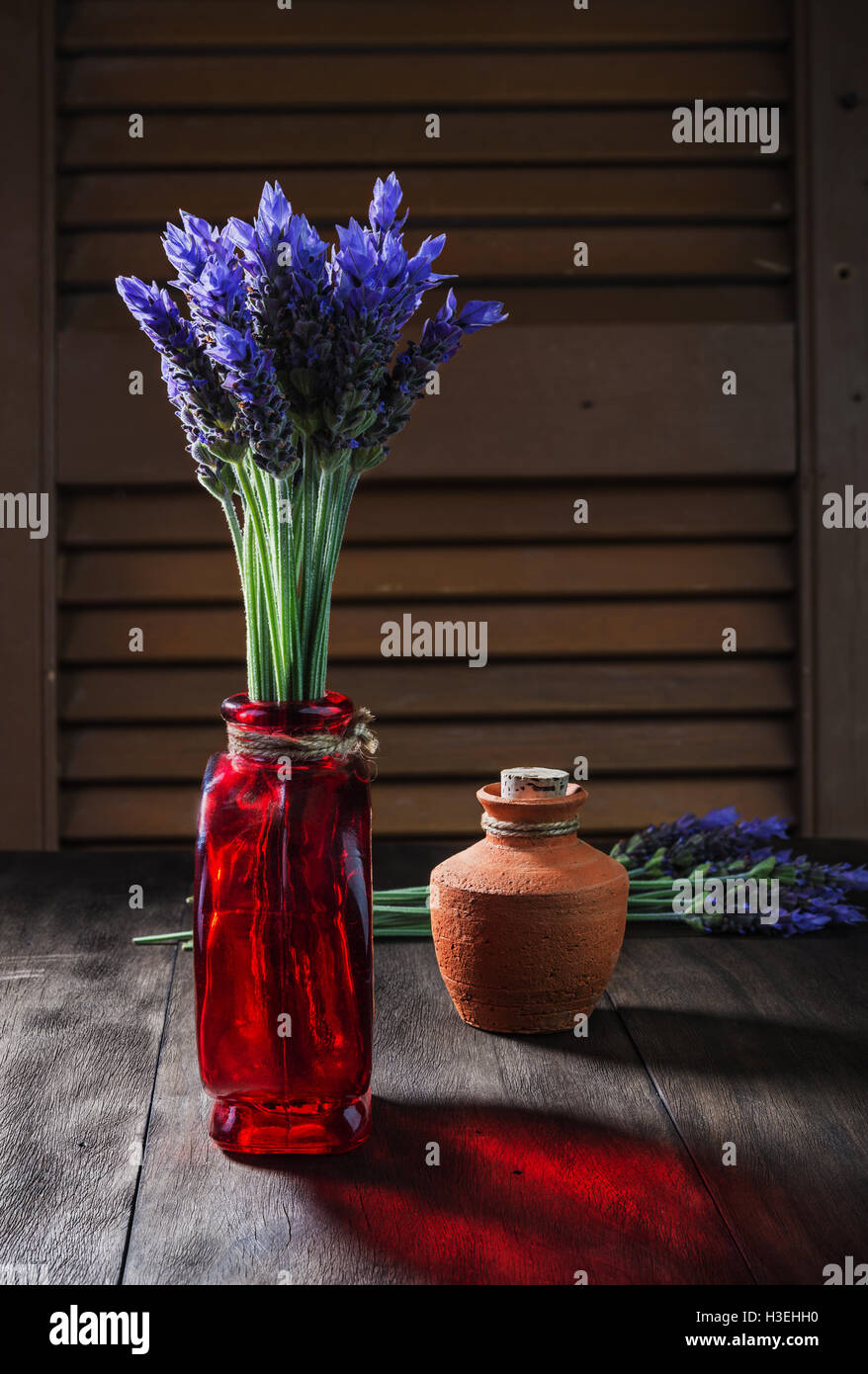 Mazzo di fiori di lavanda in vaso retrò e vaso di ceramica con olio sul vecchio sfondo di legno Foto Stock