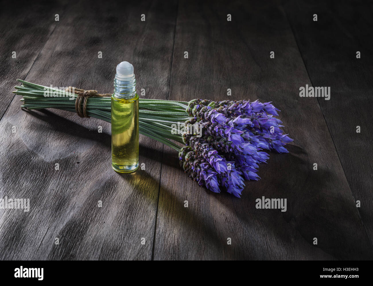 Freschi di fiori di lavanda e olio essenziale come aromaterapia naturale per il mal di testa ed emicrania di rilievo sul vecchio sfondo di legno Foto Stock