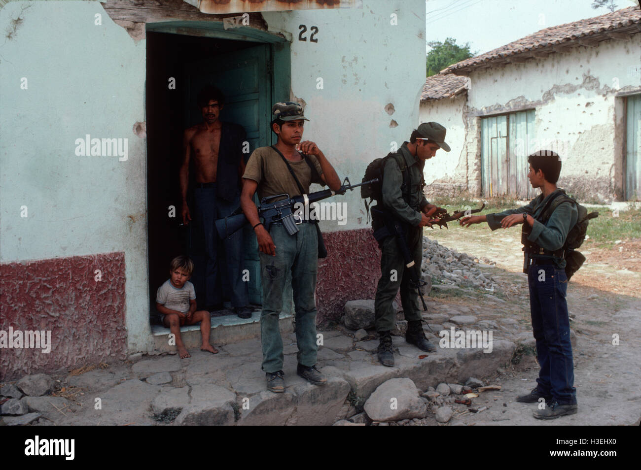 TENANCINGO, EL SALVADOR, Marzo 1984: - all'interno del FPL Guerrilla zone di controllo. Guerrilla fighter al di fuori di un negozio che ancora funzioni nella parzialmente in rovina città di Tenancingo. Foto Stock