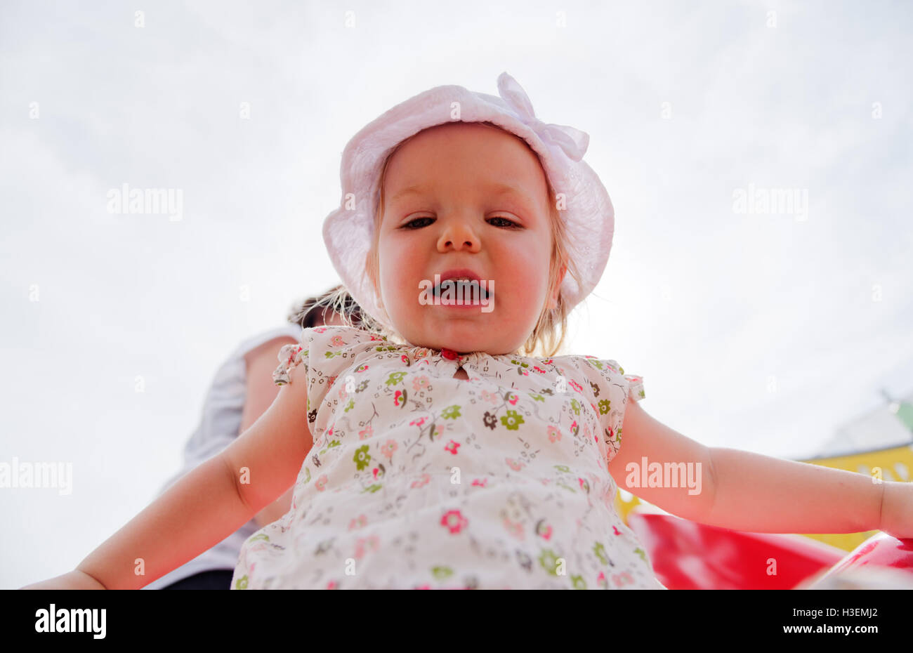 Guardando verso l'alto un sorridente ragazza giovane (2 yr old) vestita di bianco vestiti estivi Foto Stock