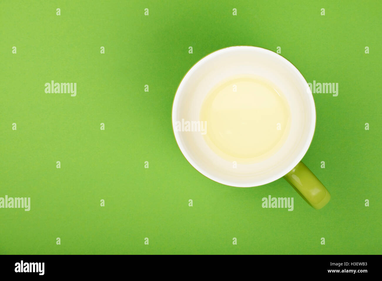 Uno vuoto finito di verde chiaro tè oolong in grande tazza con piattino sul libro verde sullo sfondo, vista dall'alto, una prospettiva aerea Foto Stock