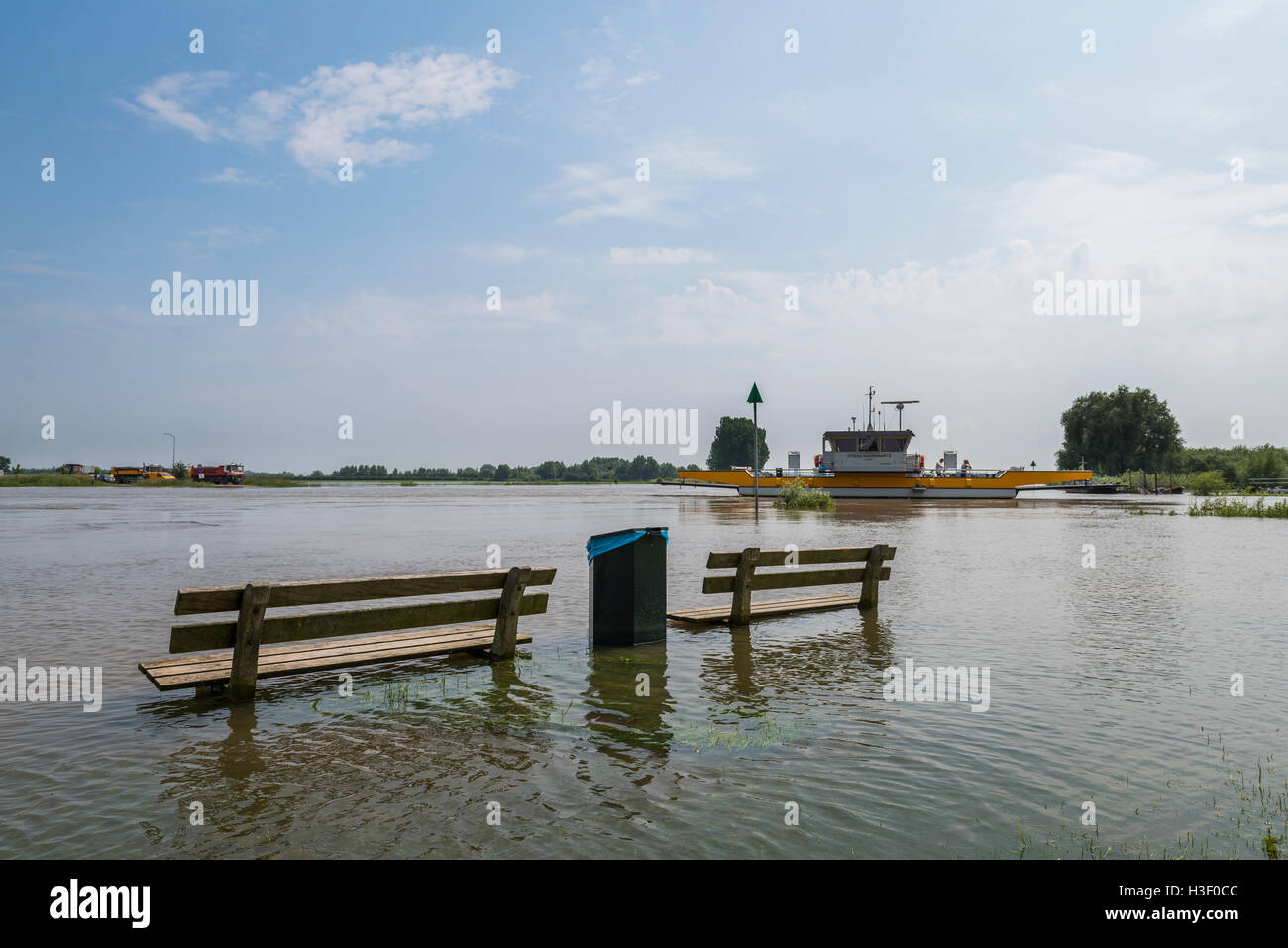 Acqua alta sul fiume IJssel con il traghetto di Dieren e due panche in acqua nei Paesi Bassi. Foto Stock