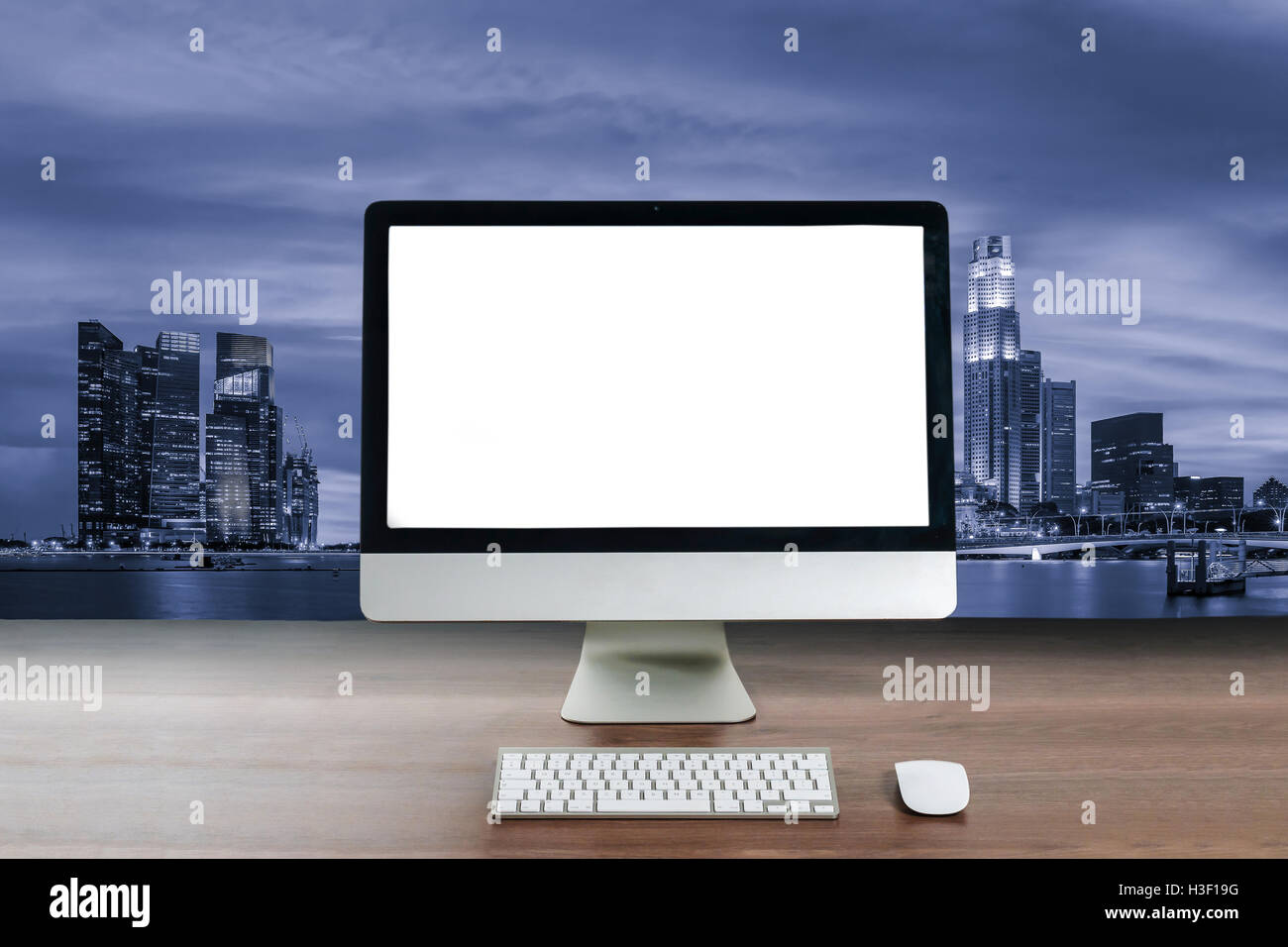 Sullo schermo del computer sul tavolo di legno nel moderno business office con la notte di Singapore centro business district. Il concetto di business. Foto Stock