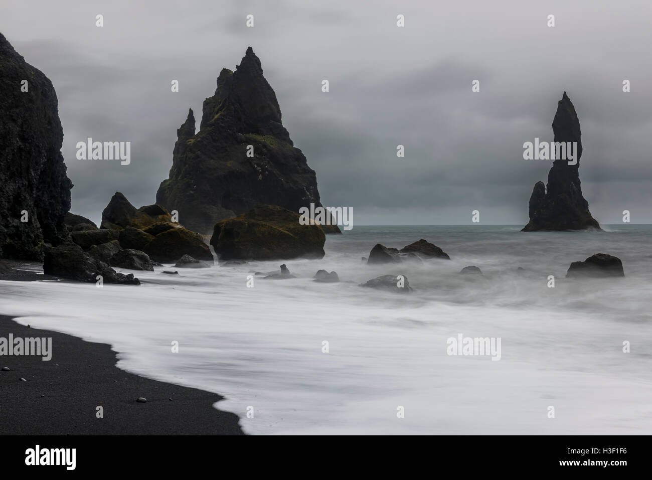 Reynishverfisvegur, Reynisfjara spiaggia di sabbia nera con rocce, oceano e oscura pioggia e nuvole temporalesche nei pressi del villaggio di Vik in Ic Foto Stock