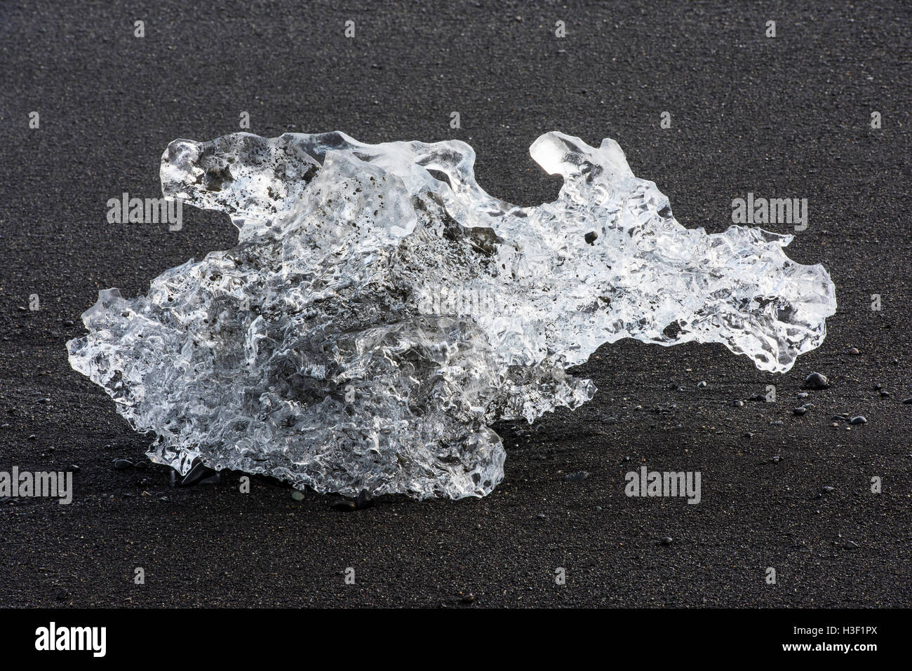 Piccolo blocco di ghiaccio al di lava nera in spiaggia la sera vicino al fiume Jokulsa a Jokulsarlon laguna glaciale in Vatnajokull. Foto Stock