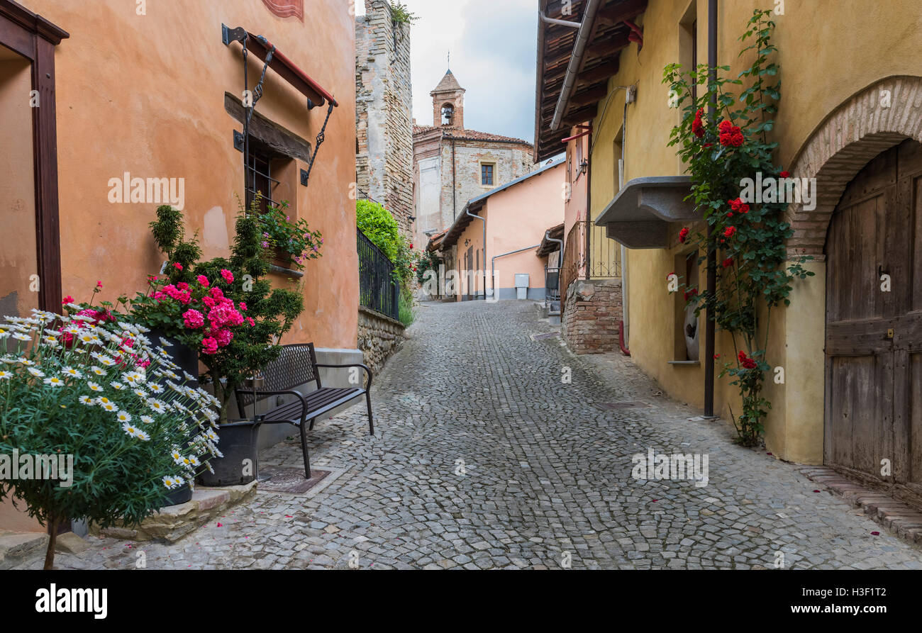 Pittoresca strada in Monforte d'Alba, Piemonte, Italia con rose, case colorate e chiesa. Foto Stock