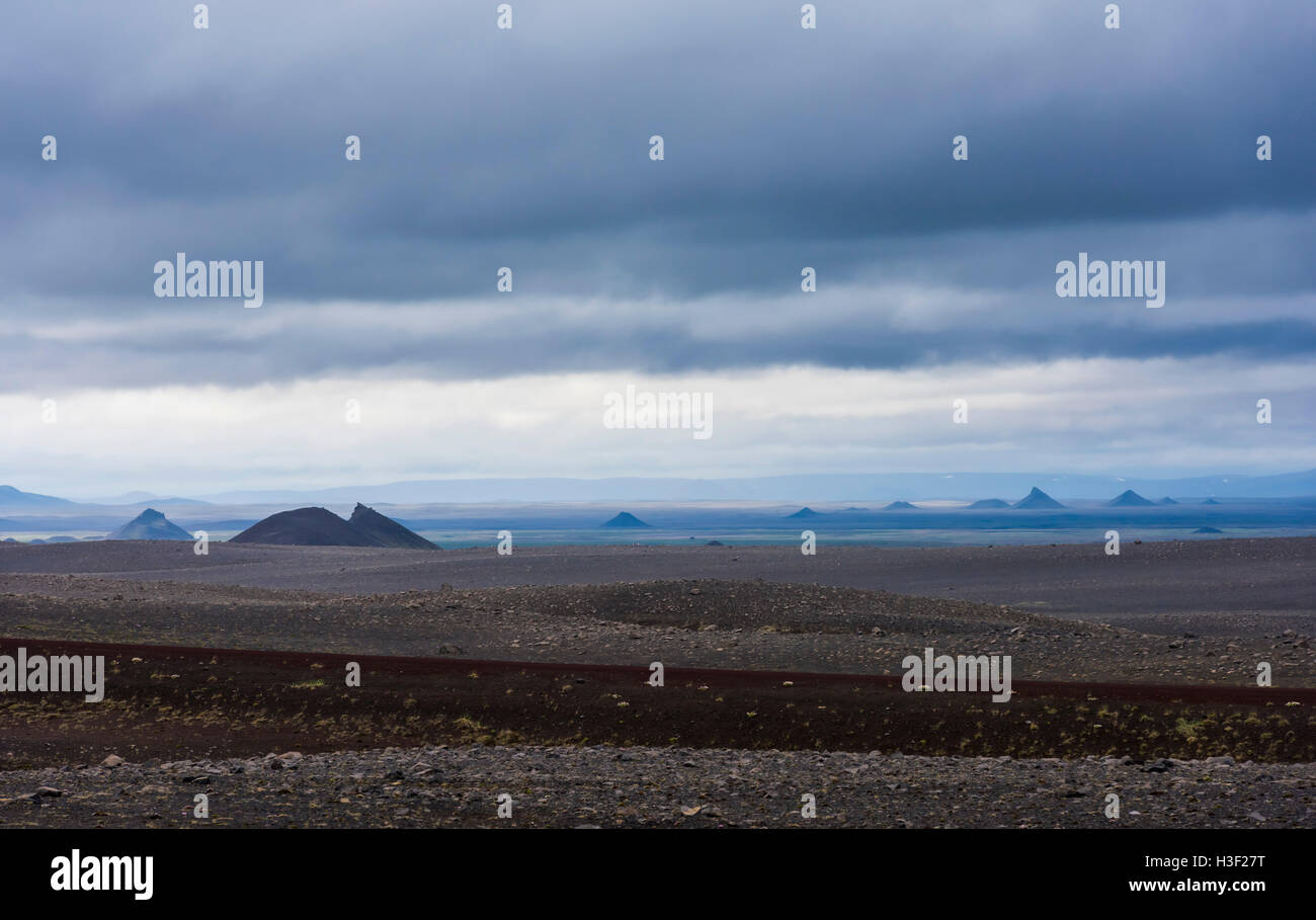 Paesaggio vulcanico su Islanda con montagne, fiumi di lava e sabbia nera e oscura pioggia nuvole nel cielo. Foto Stock
