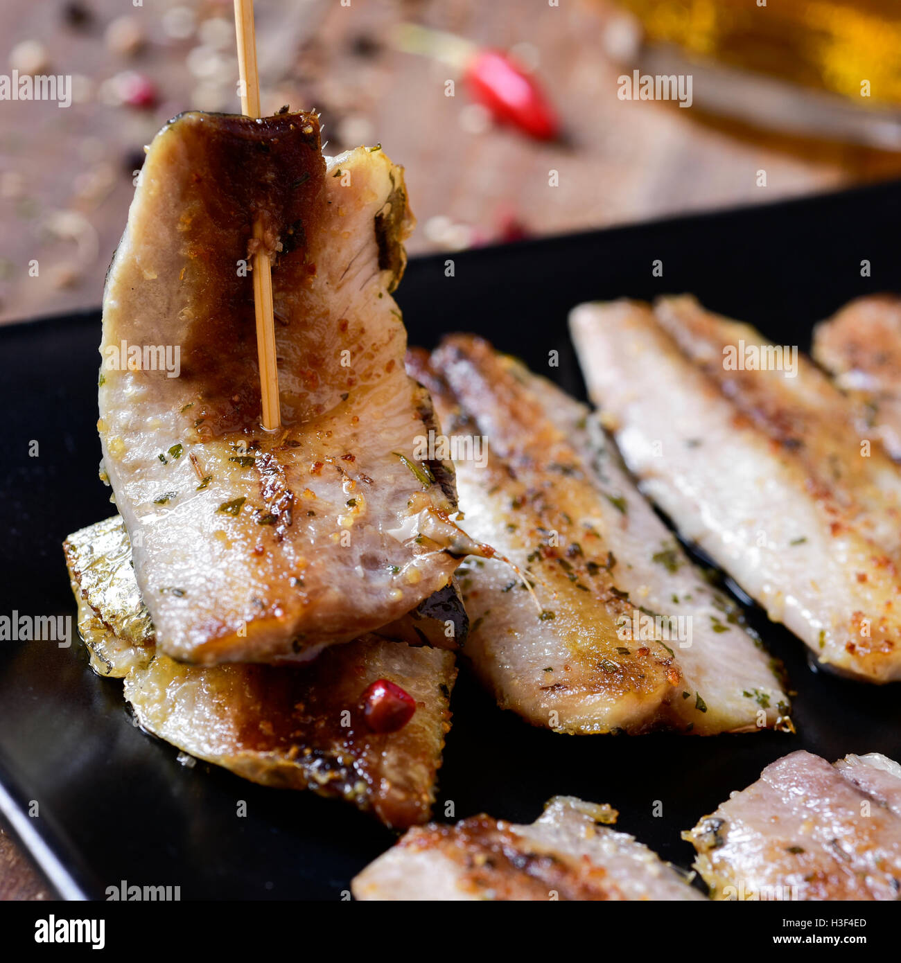 Ingrandimento di una piastra con un po' di spagnolo di filetti di sardine è servita come tapas, su una tavola in legno rustico Foto Stock
