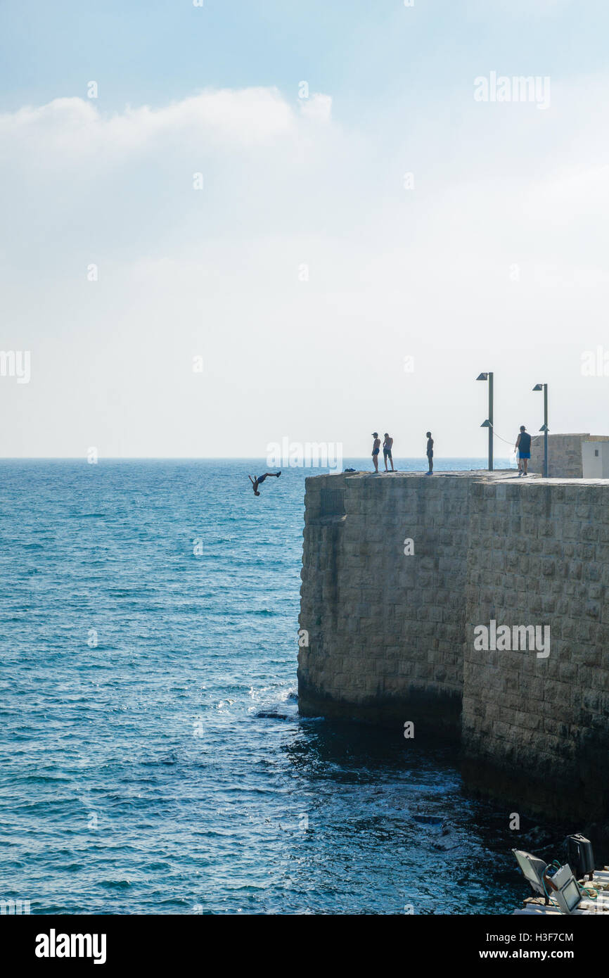 ACRE, Israele - Agosto 03, 2016: giovane salta al mare dalla sommità delle antiche mura di Acri, Israele. Acre è uno dei Foto Stock