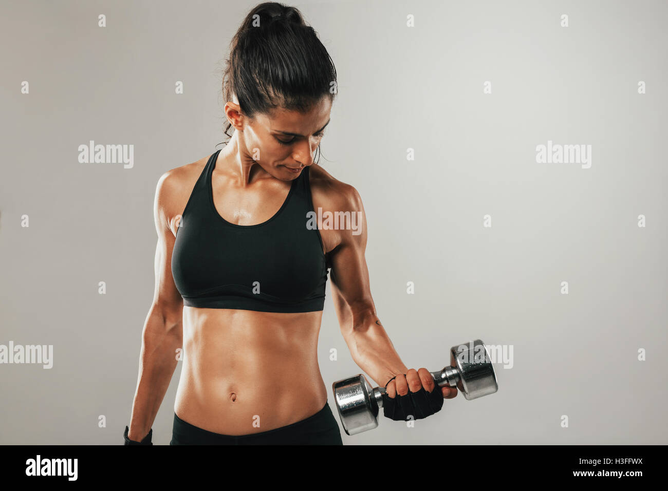 Attraente giovane donna con un accoppiamento corpo tonico lavora con pesi sollevamento pesi per rafforzare i suoi muscoli addominali e Foto Stock