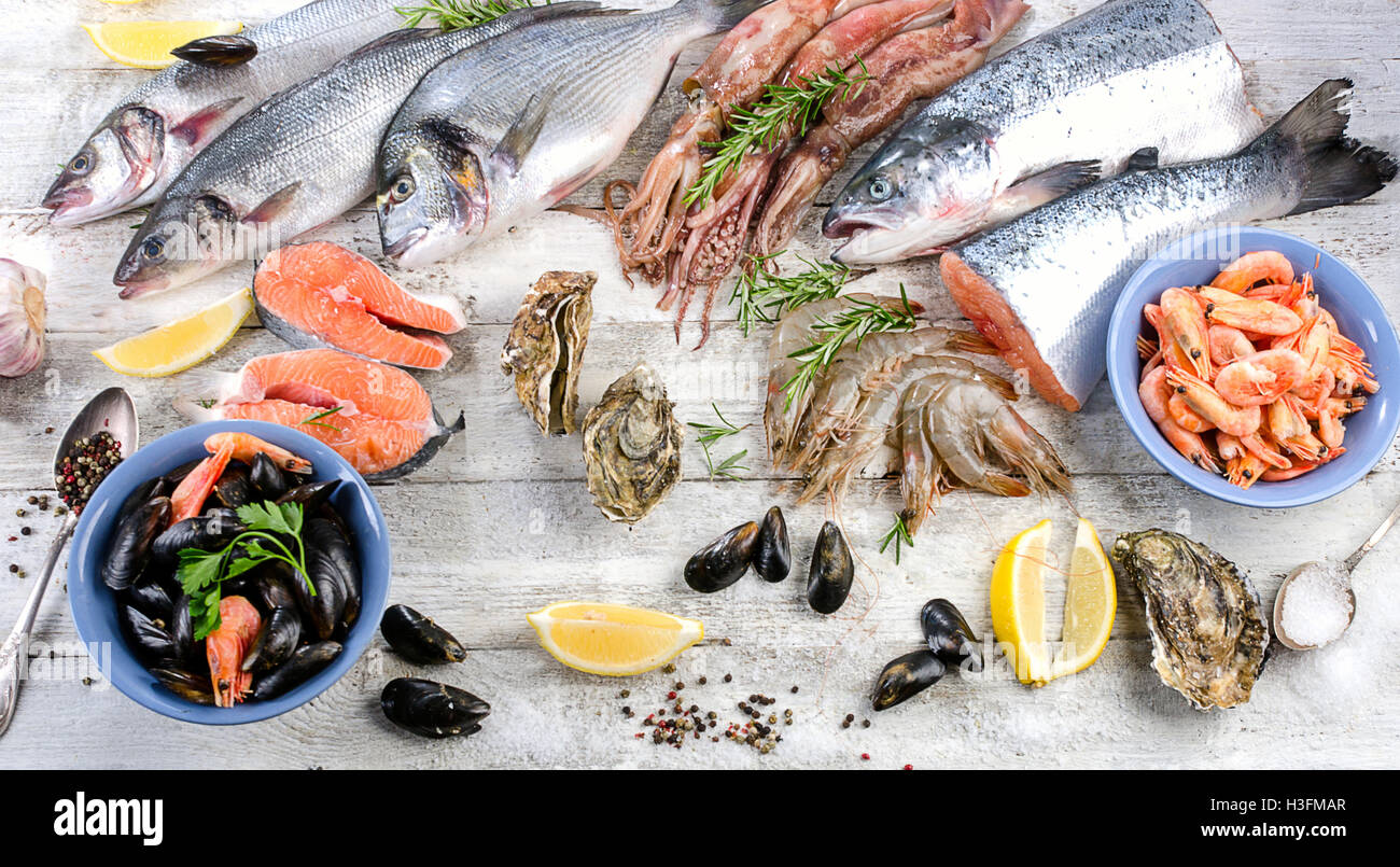 Pesce fresco e altri piatti di pesce su un bianco sullo sfondo di legno. Lay piatto Foto Stock