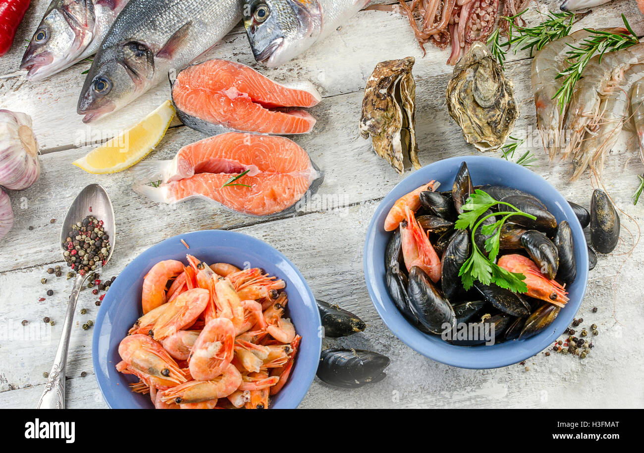 Pesce fresco e altri piatti di pesce su un sfondo di legno. Lay piatto Foto Stock