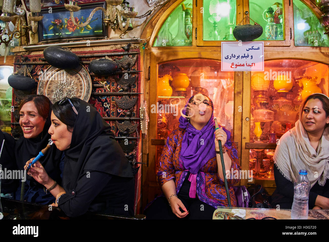 Iran, Isfahan, Azadegan teahouse, giovani donne di fumare un tubo di acqua Foto Stock