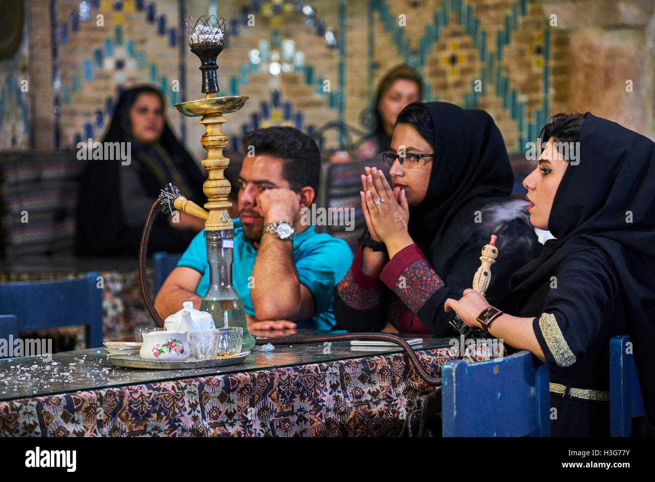 Iran, Kerman provincia, Kerman, Vakil hammam teahouse, donna iraniana di fumare un tubo di acqua Foto Stock