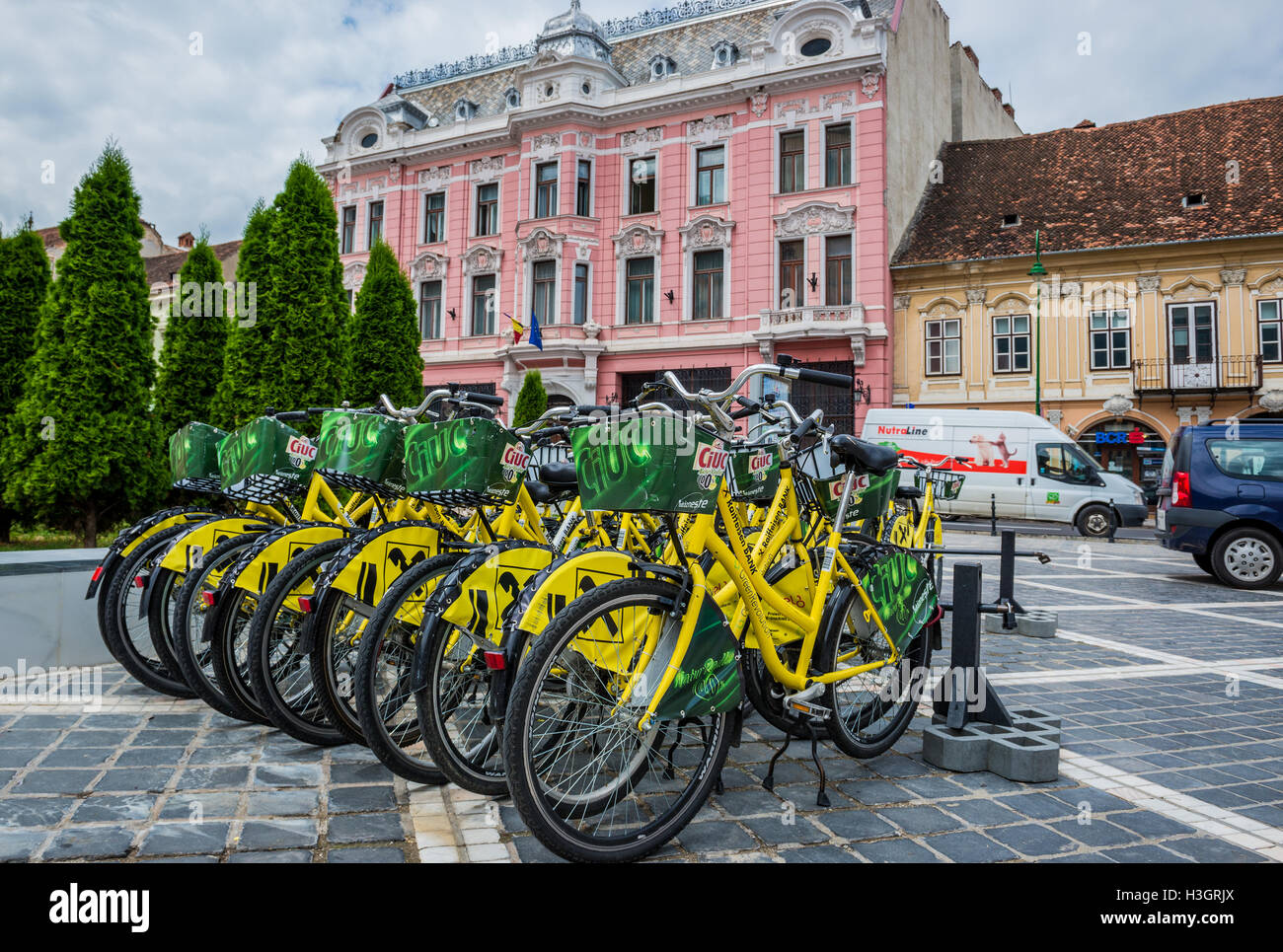 Banca Raiffeisen urban bikes in Brasov, Romania. La Banca nazionale di Romania edificio sullo sfondo Foto Stock