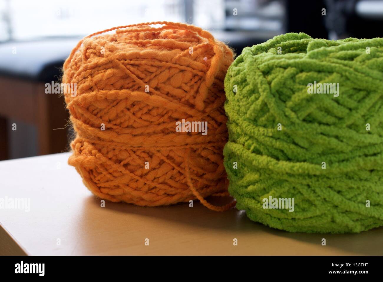 Palle di cotone di lana filati di seta su tavola in legno di colore arancione e verde Foto Stock