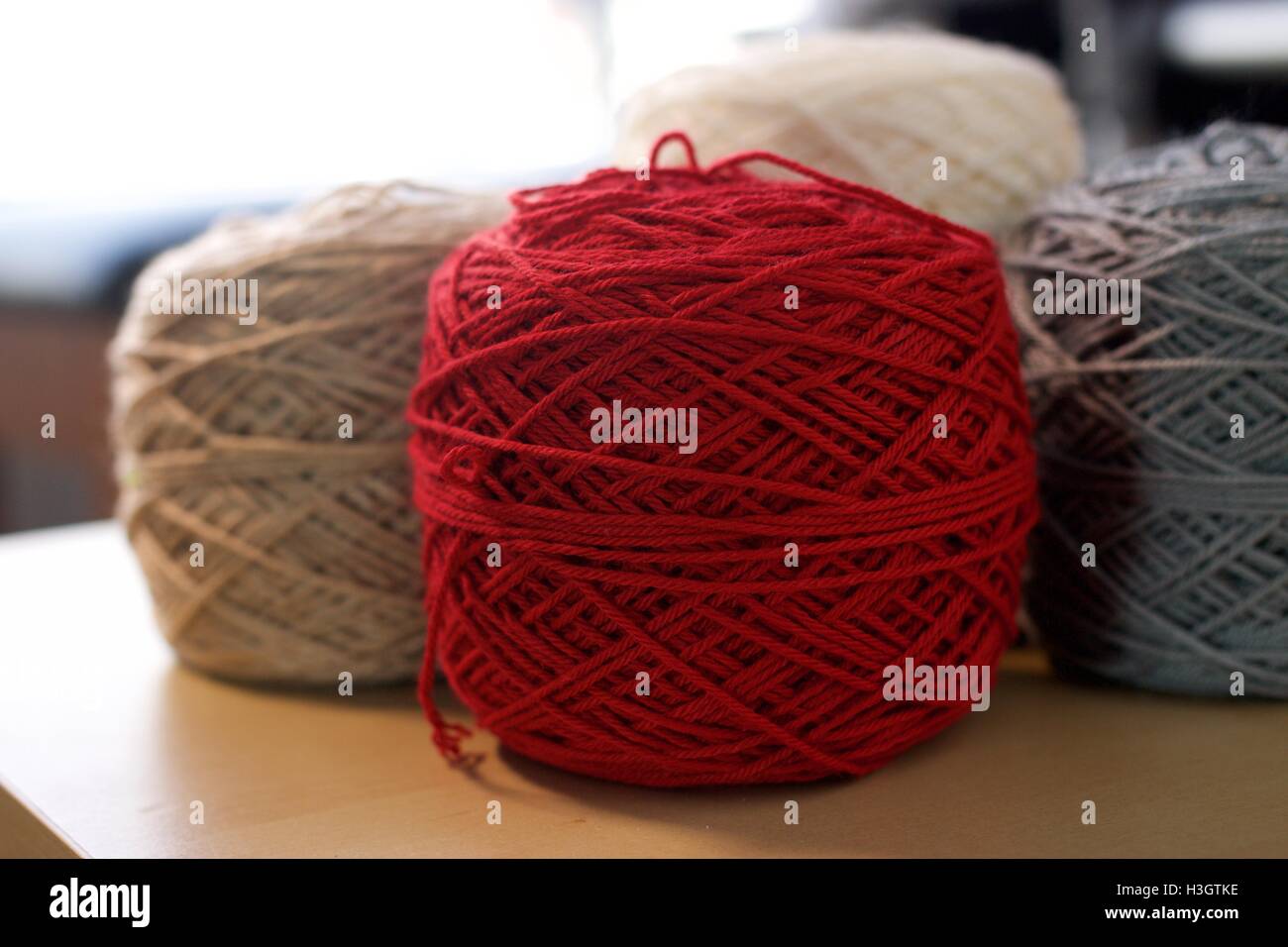 Palle di cotone di lana filati di seta su tavola in legno grigio rosso bianco e marrone Foto Stock