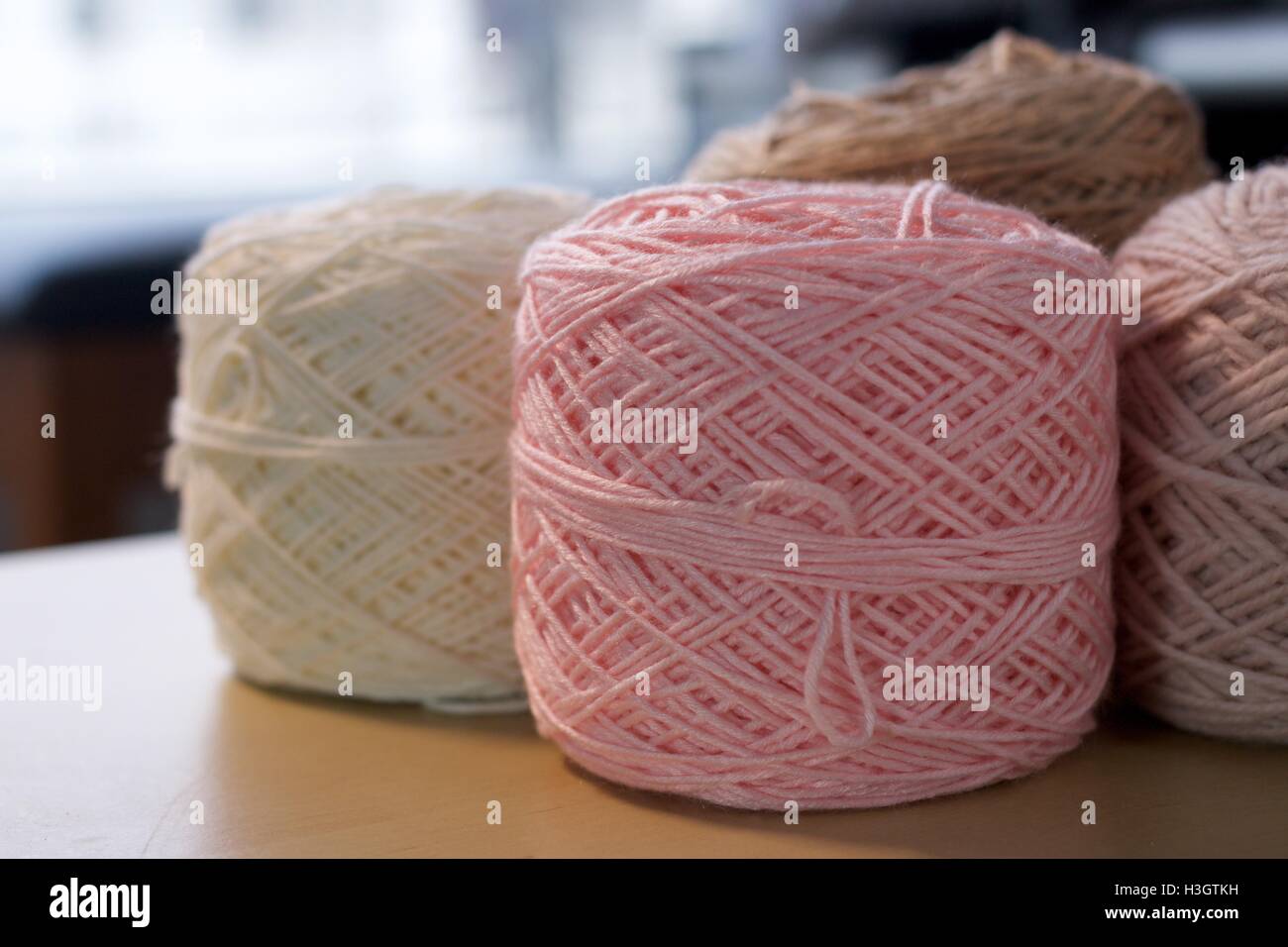 Palle di cotone di lana filati di seta su tavola in legno di rosa bianco e marrone Foto Stock