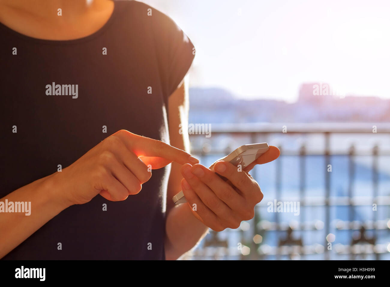 Giovane donna adulta utilizzando uno smartphone al tramonto Foto Stock