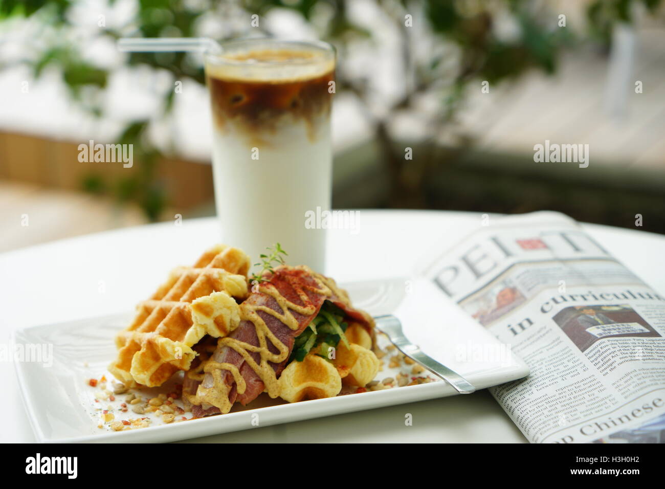 Fresche colazioni fatte in casa a cialde, con ghiaccio caffè e giornale Foto Stock