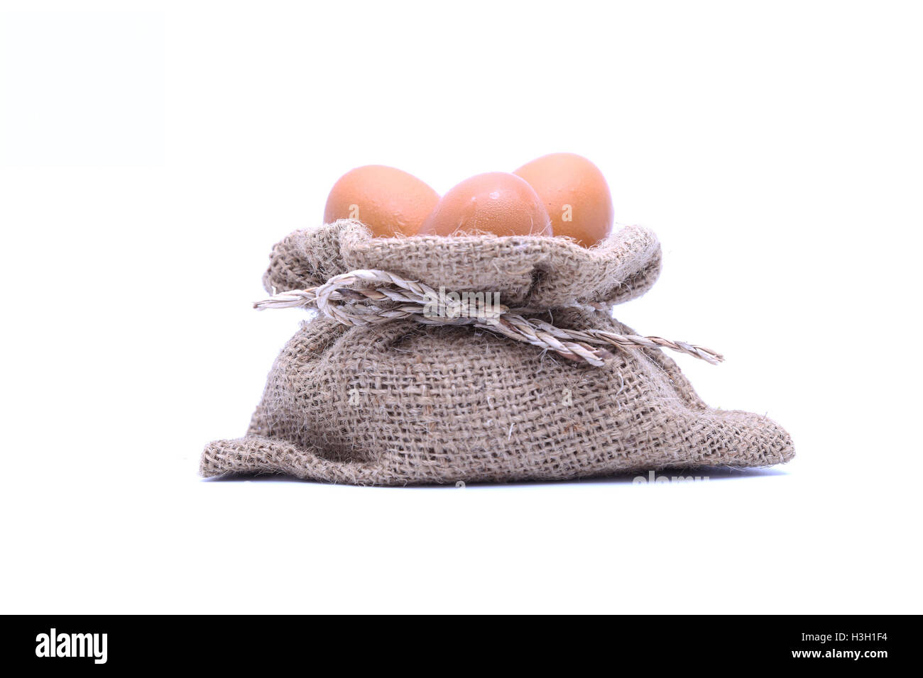 Uova di colore marrone nel sacco marrone su bianco isolato Foto Stock