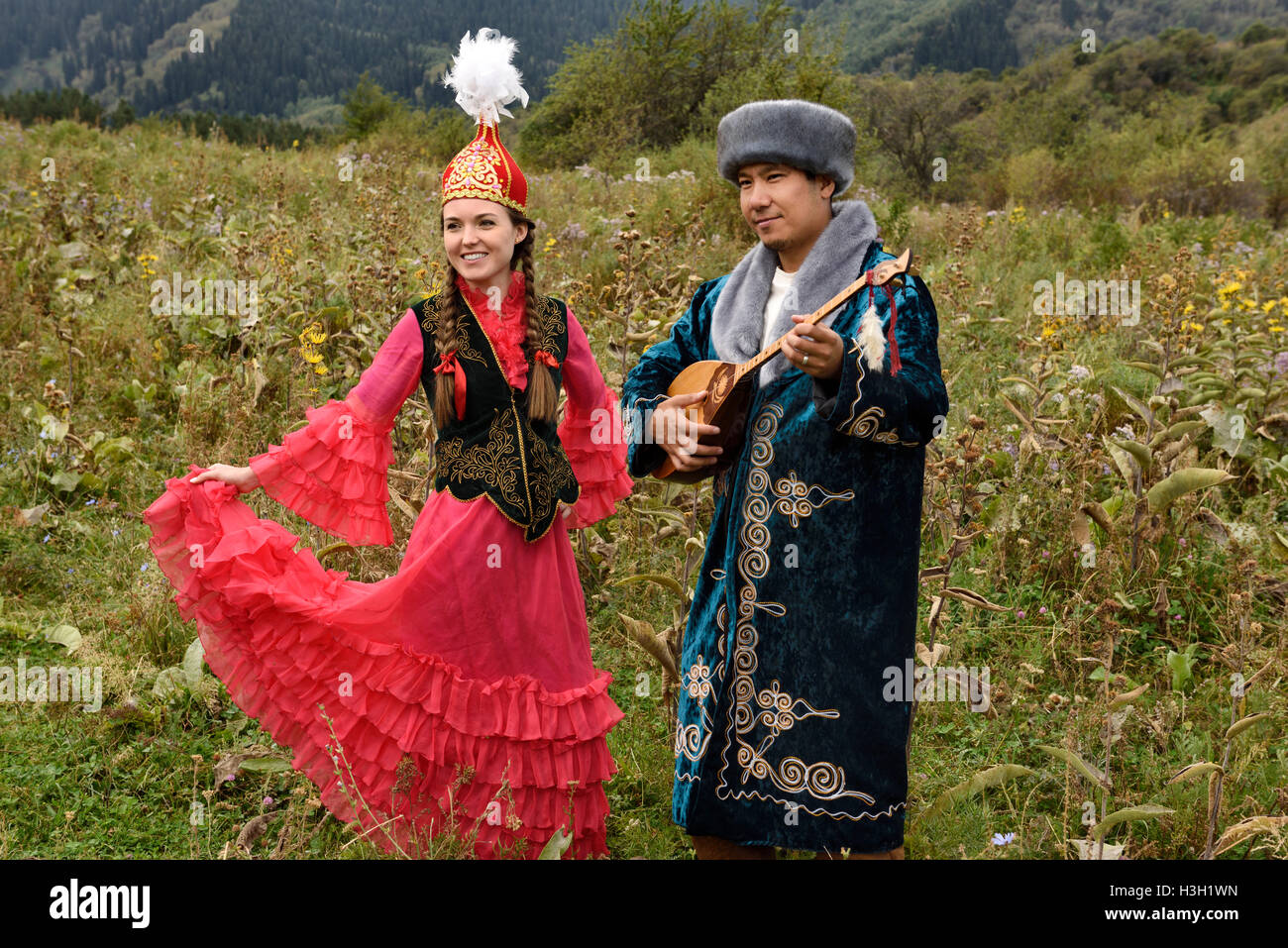 Giovane uomo e donna nel tradizionale abbigliamento kazako in un campo al villaggio degli unni Kazakistan in autunno Foto Stock