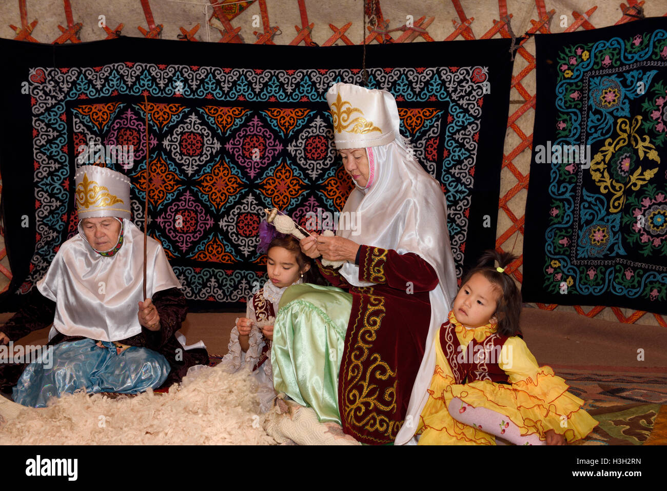 Nonne e bambini in yurta di battitura e la filatura della lana Unni village Kazakistan Foto Stock