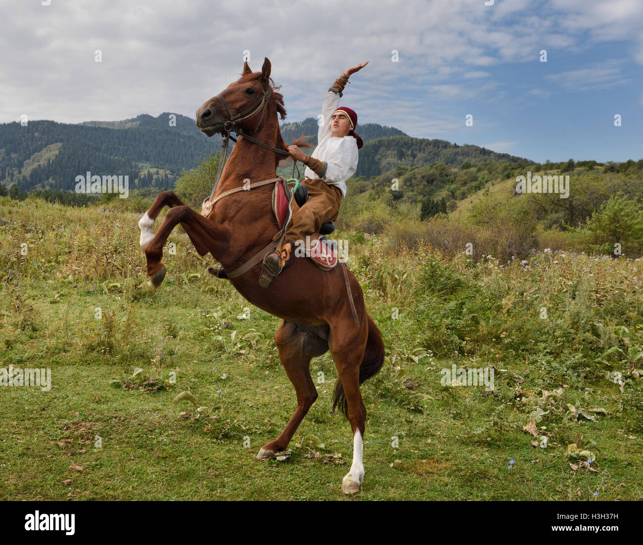 Il kazako horse rider con il braccio sollevato su allevamento castrazione nel villaggio degli Unni Kazakistan Foto Stock