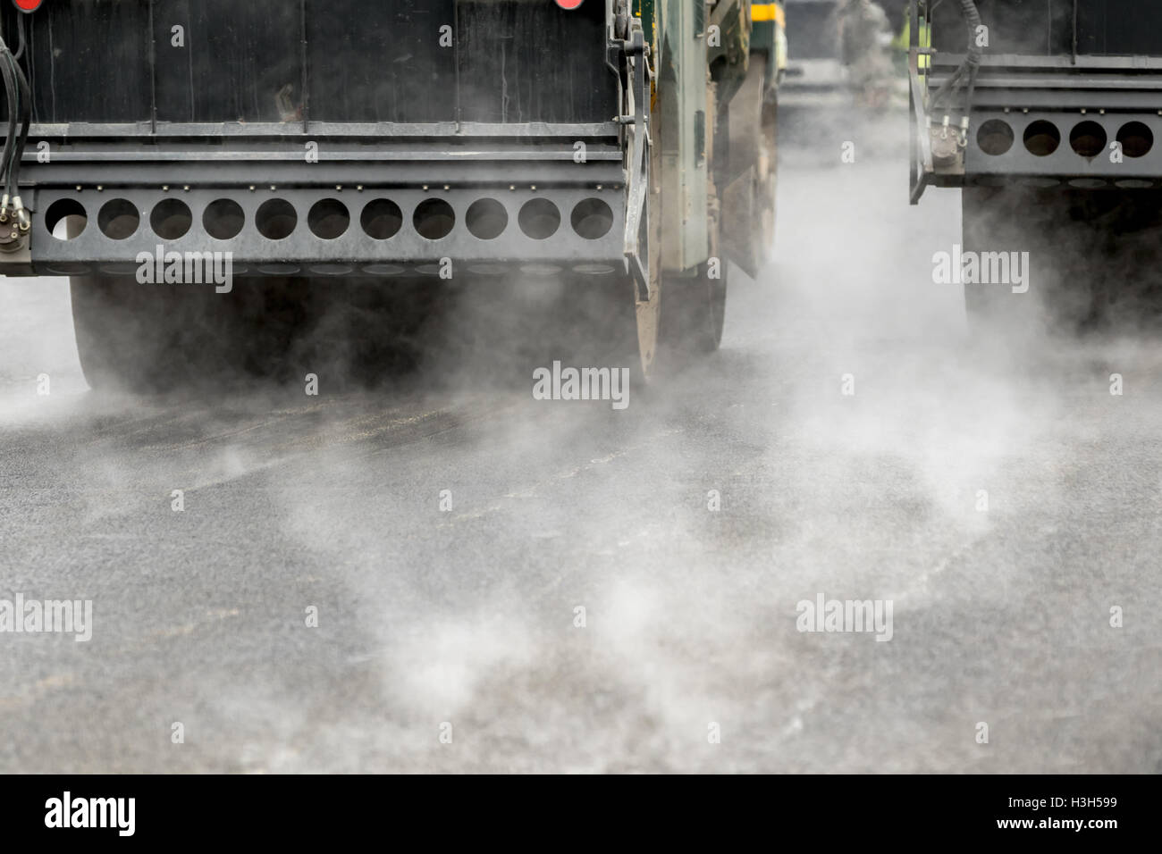 Strada macchine per la laminazione di lavorare con vapore sull'asfalto Foto Stock