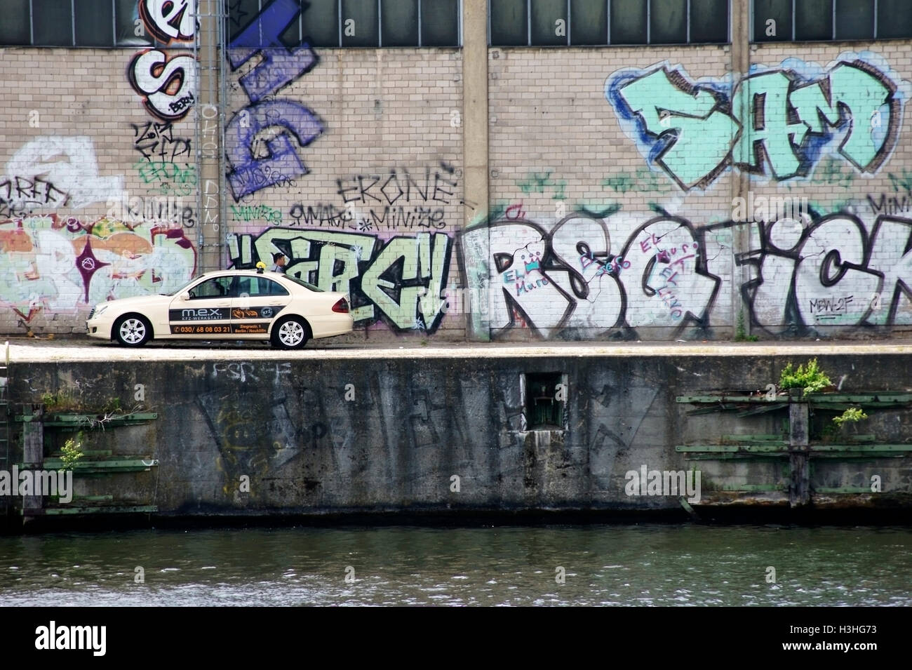 Taxi di fronte dipinto luminosamente muro di graffiti Foto Stock