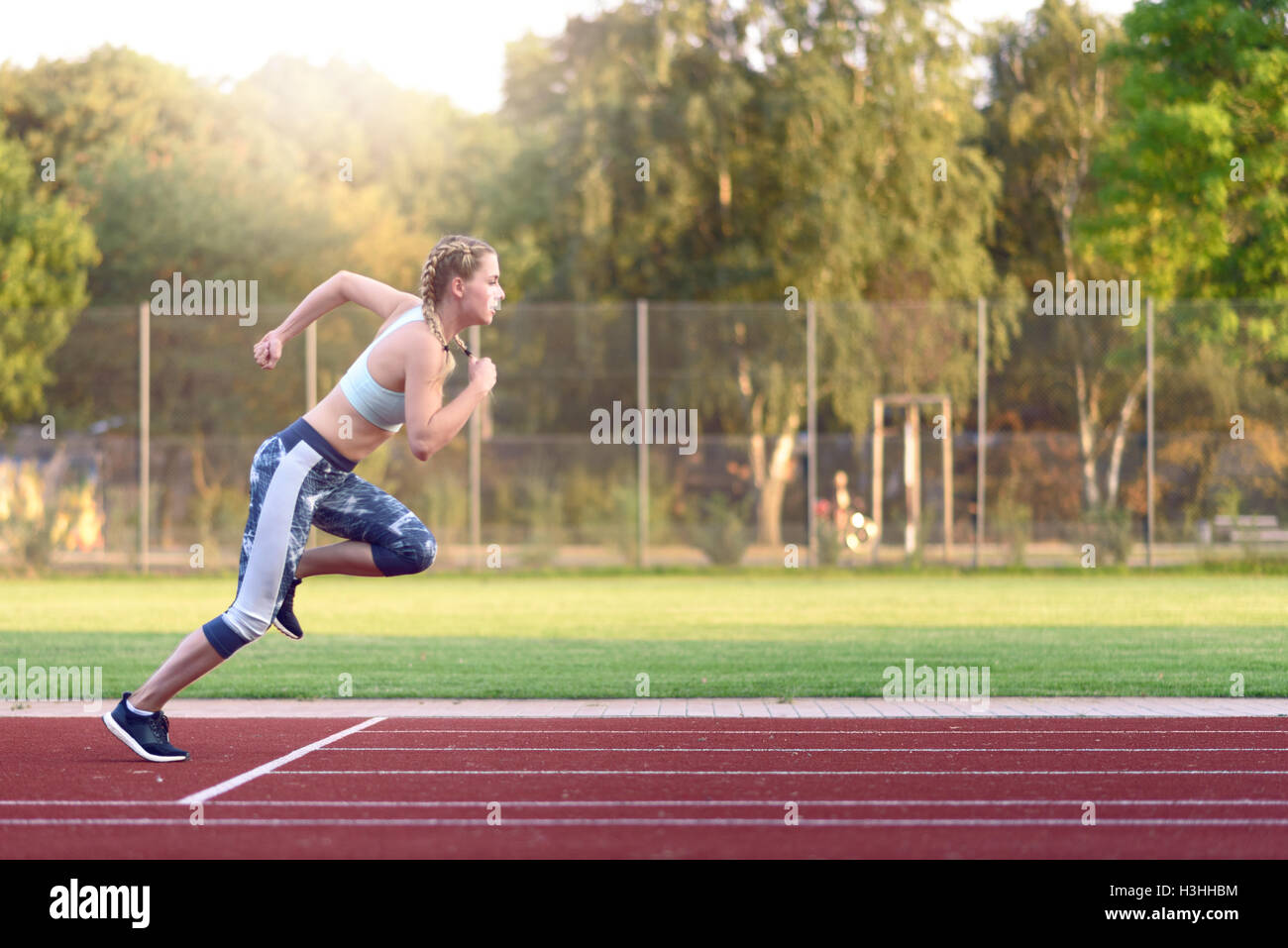 Atleta femminile di formazione per una gara come da prassi ha il suo inizio per uno sprint a tempo su un outdoor sports via Foto Stock
