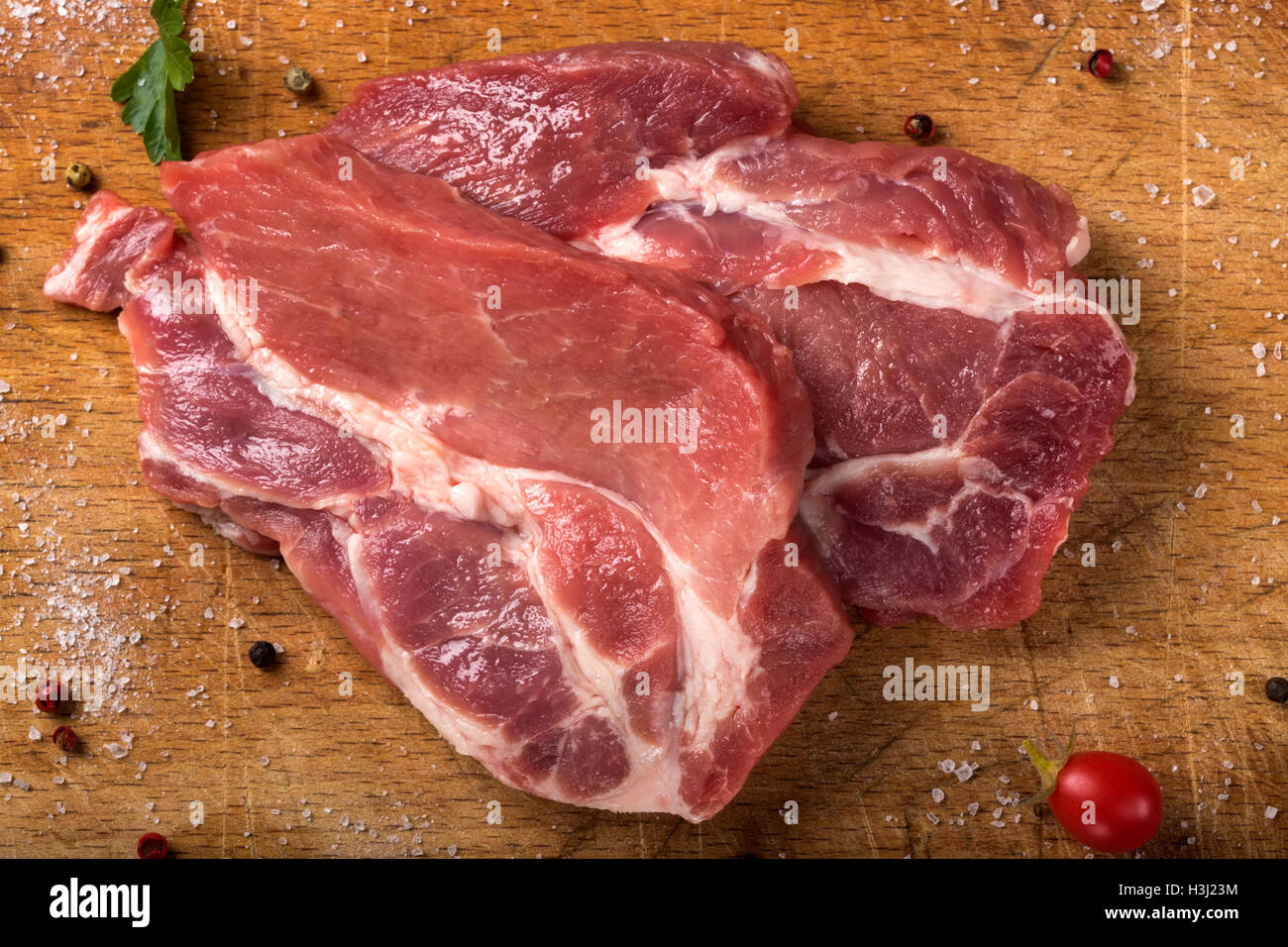 Carne di maiale cruda bistecche sulla tavola di legno con erbe aromatiche Foto Stock