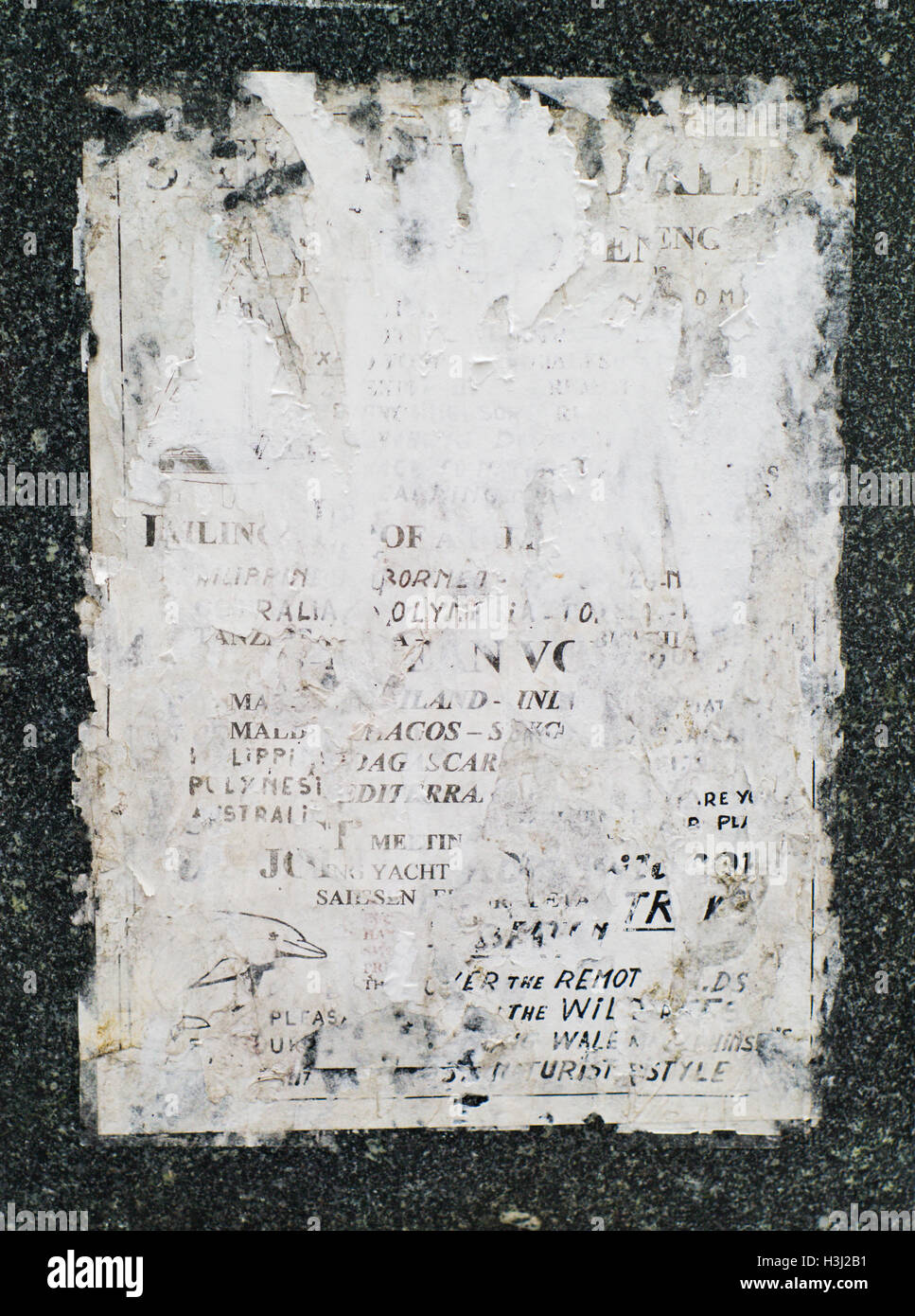 Closeup shot di vecchi, sbiaditi e strappato poster sulla parete di granito Foto Stock