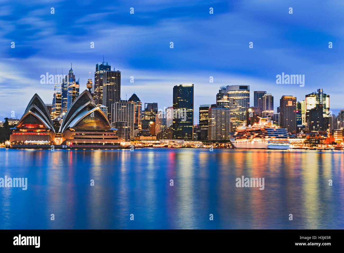 Paesaggio urbano della città di Sydney CBD attraverso il porto di sunrise riflettendo le luci dei grattacieli e punto di riferimento importante in ancora blurr Foto Stock