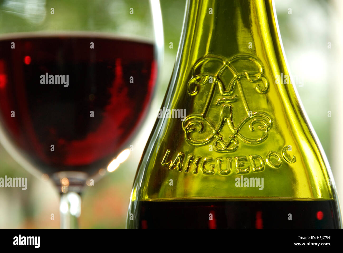 BOTTIGLIA DI VINO ROSSO LANGUEDOC ALL'APERTO e bicchiere di Languedoc Francese vino rosso sul tavolo soleggiato all'aperto Foto Stock