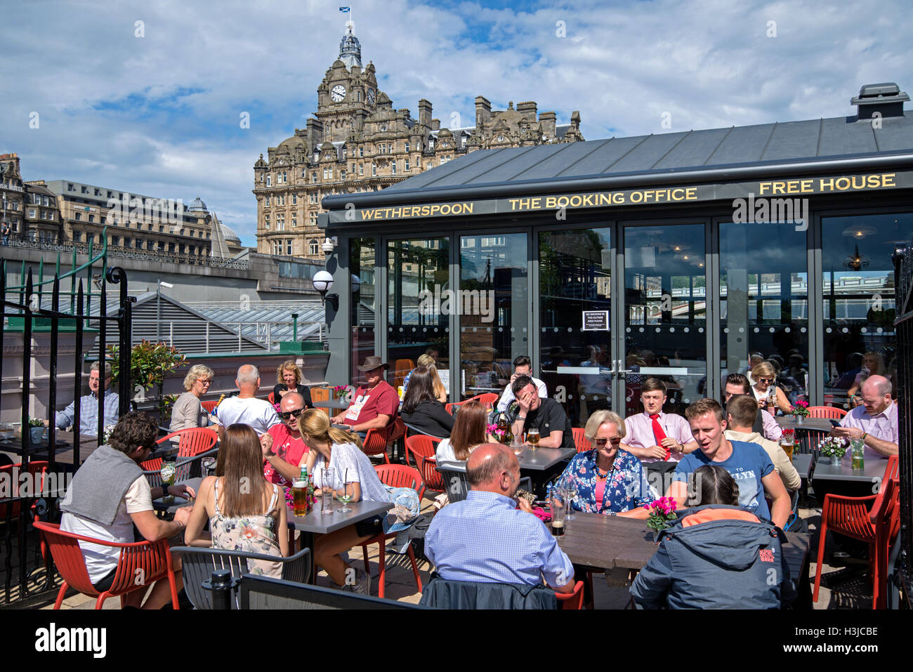 I clienti gustando un drink presso Wetherspoon su Waverley Bridge, Edimburgo con il Balmoral Hotel in background. Foto Stock