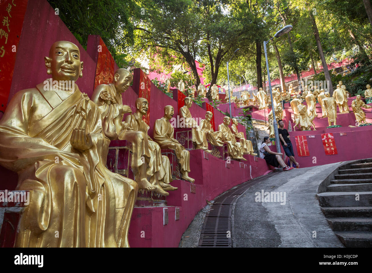 Giovane appoggiato accanto a decine di golden statue di Buddha lungo il percorso per il Monastero dei Diecimila Buddha (l'uomo grasso Tsz) in Hong Kong Foto Stock
