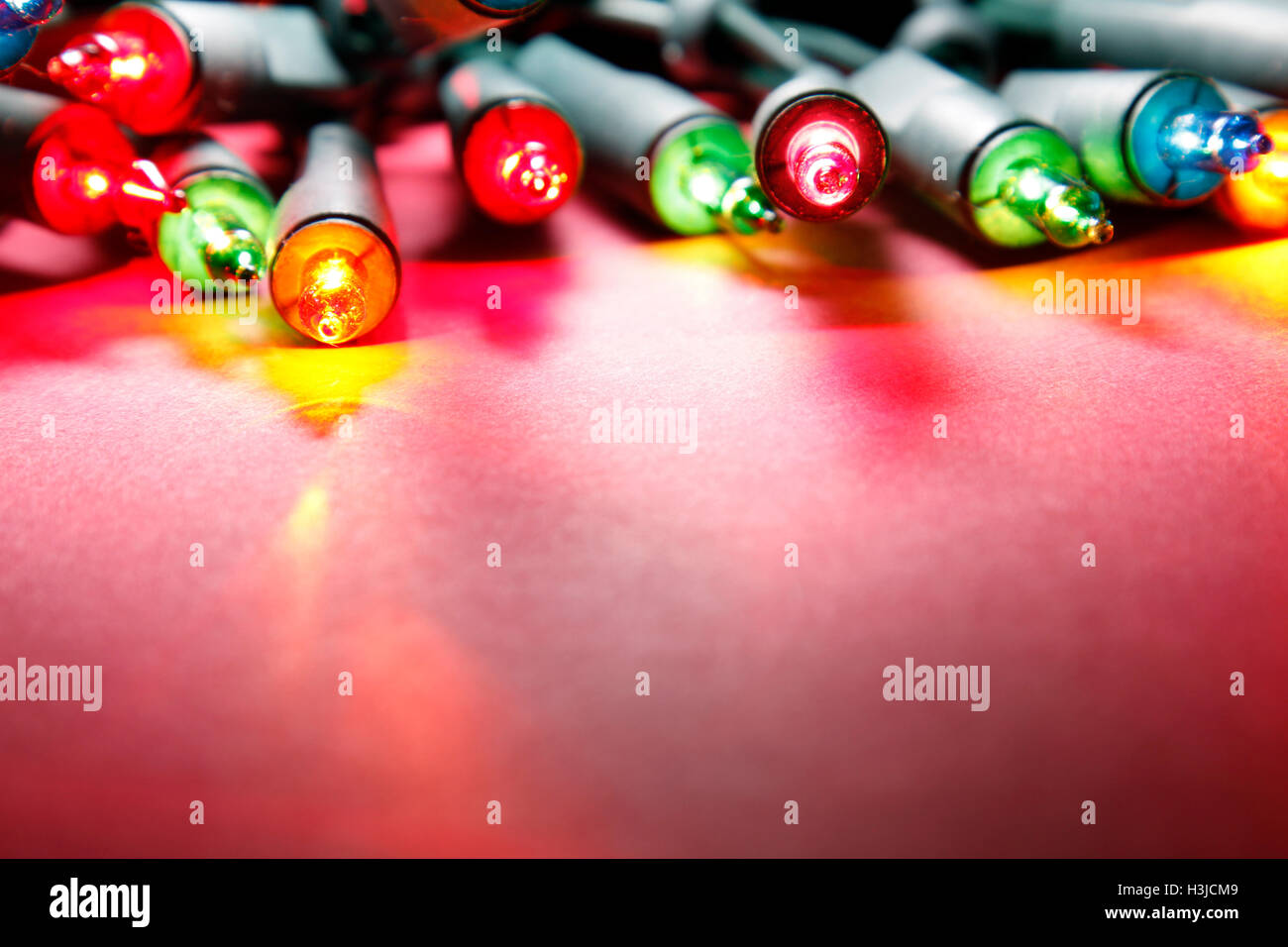 Primo piano di luci di Natale incandescente su sfondo rosso Foto Stock