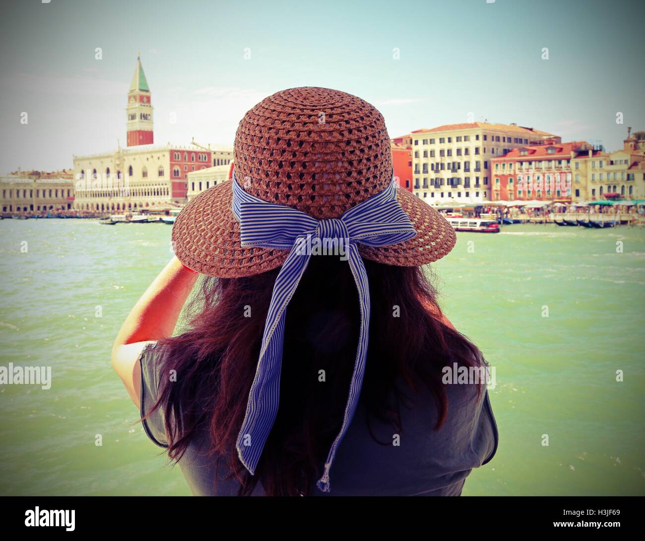 Bella donna con capelli lunghi marrone e un ampio cappello di paglia a Venezia con effetto Foto Stock