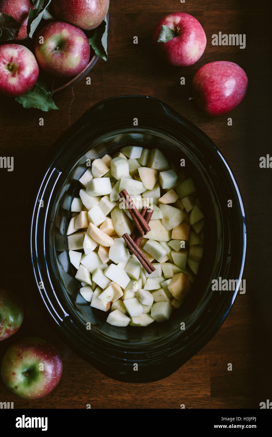 Affettato e sbucciate le mele sono posti nella coppa di un slow cooker - fotografata dalla vista dall'alto. Foto Stock