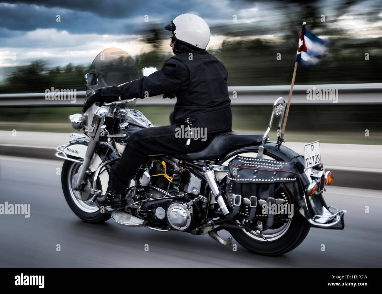 Uomo a cavallo di un Harley Davidson Moto a velocità, con gagliardetto cubano, Cuba Foto Stock