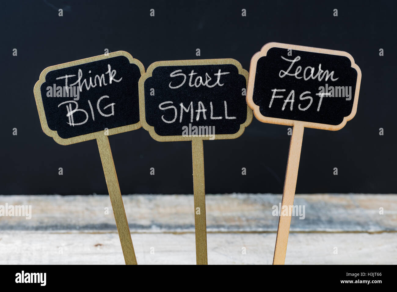 Messaggio di Business pensare in grande, inizia a piccoli passi, impara velocemente scritto con un gessetto su legno mini etichette di Blackboard Foto Stock